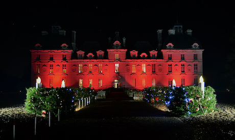 Le château de Cheverny illuminé en rouge avec une couronne géante de Noël éclairée dans la nuit.