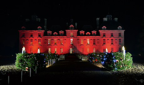 Le château de Cheverny illuminé en rouge avec une couronne géante de Noël éclairée dans la nuit.